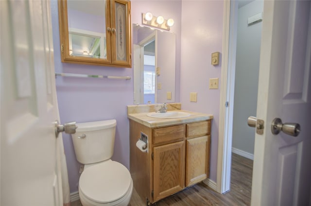 half bathroom with toilet, baseboards, wood finished floors, and vanity