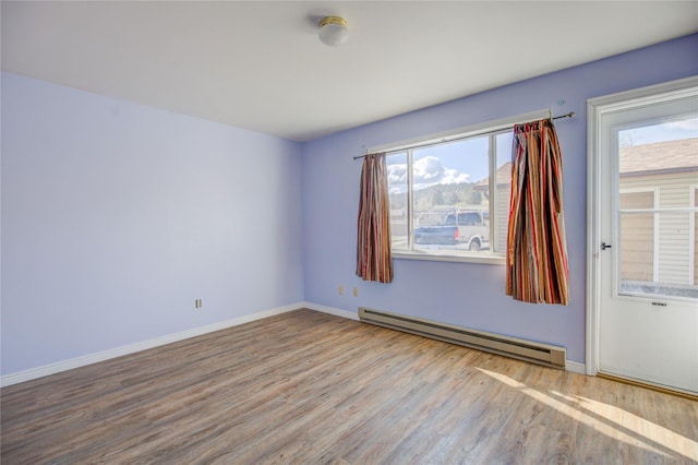 empty room featuring a baseboard radiator, plenty of natural light, and wood finished floors