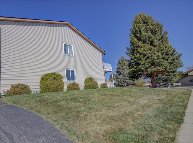 view of side of property with a balcony and a lawn