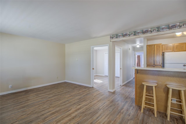 2449 Belt View Dr Unit B, Helena, MT 59601 - kitchen with freestanding refrigerator, baseboards, dark wood-type flooring, and a breakfast bar area