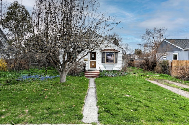 view of front of house featuring entry steps, fence, and a front lawn
