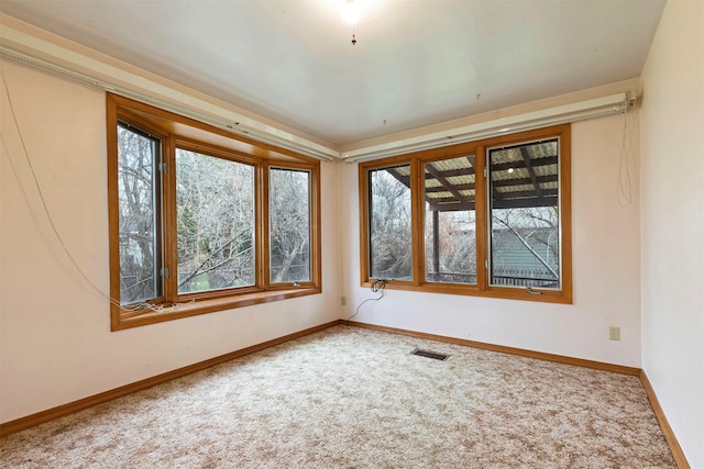 carpeted spare room featuring visible vents and baseboards