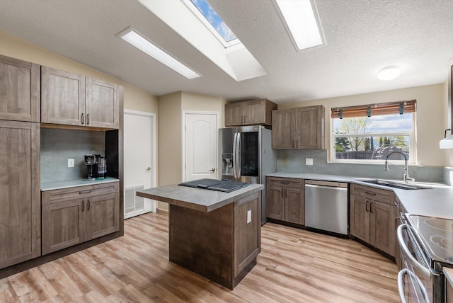 61574 Hillside Rd, Saint Ignatius, MT 59865 - kitchen featuring light wood finished floors, stainless steel appliances, a center island, and a sink