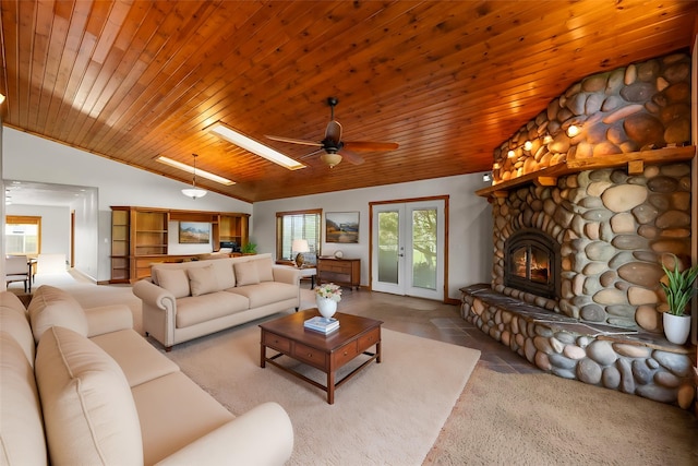 61574 Hillside Rd, Saint Ignatius, MT 59865 - carpeted living area featuring a ceiling fan, a stone fireplace, lofted ceiling with skylight, and wooden ceiling