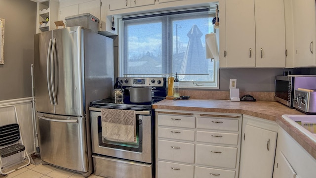 kitchen featuring white cabinets, light countertops, appliances with stainless steel finishes, and light tile patterned floors