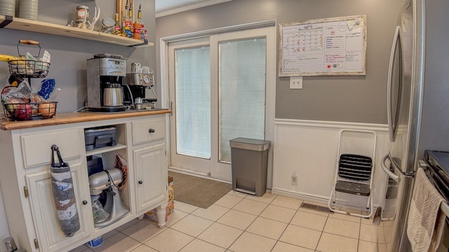 kitchen featuring a wainscoted wall, ornamental molding, open shelves, light tile patterned floors, and white cabinets