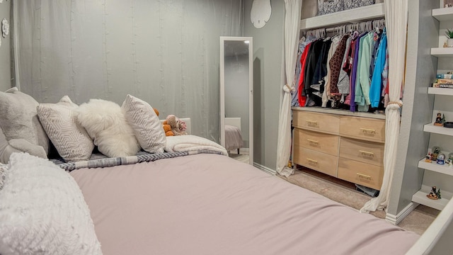 bedroom featuring light carpet, baseboards, and a closet