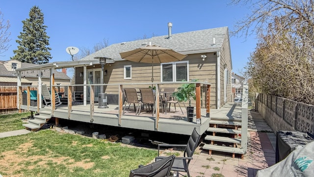 back of property featuring a lawn, a deck, a shingled roof, and a fenced backyard
