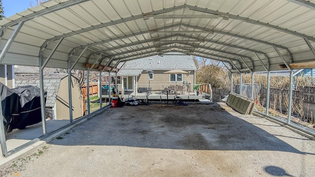 view of parking / parking lot with fence and a carport