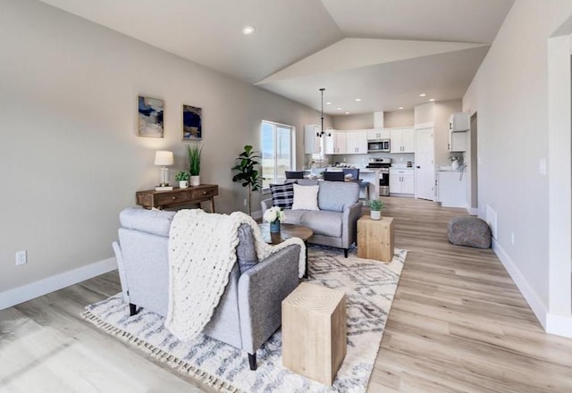 living area featuring baseboards, light wood-style floors, and vaulted ceiling