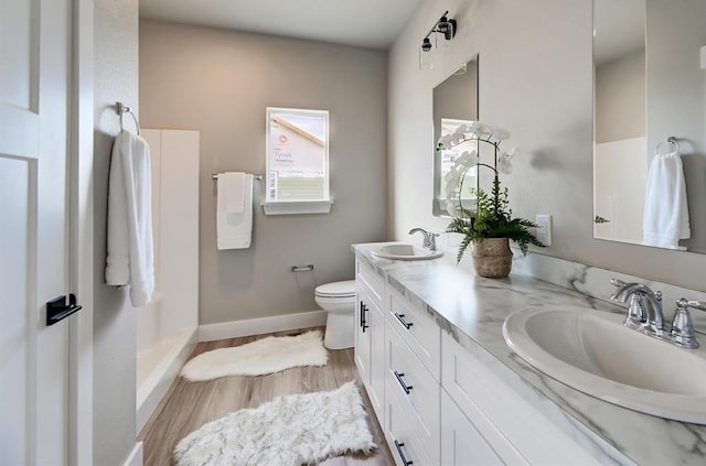 bathroom featuring a sink, double vanity, toilet, and wood finished floors