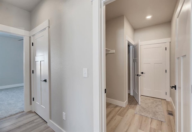 corridor featuring light wood-type flooring, recessed lighting, baseboards, and visible vents