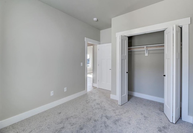 unfurnished bedroom featuring carpet flooring, baseboards, and a closet