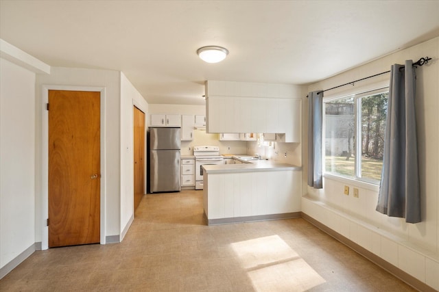 172 Holt Dr Unit A, B & C, Bigfork, MT 59911 - kitchen featuring a peninsula, freestanding refrigerator, light floors, white cabinetry, and electric stove