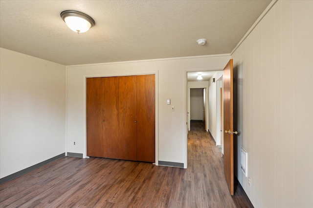 172 Holt Dr Unit A, B & C, Bigfork, MT 59911 - unfurnished bedroom with a closet, a textured ceiling, baseboards, ornamental molding, and dark wood-style floors