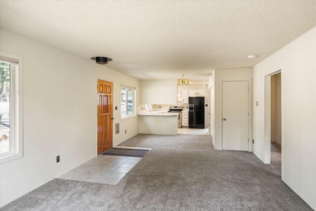 172 Holt Dr Unit A, B & C, Bigfork, MT 59911 - unfurnished living room with light colored carpet, a wealth of natural light, and a notable chandelier