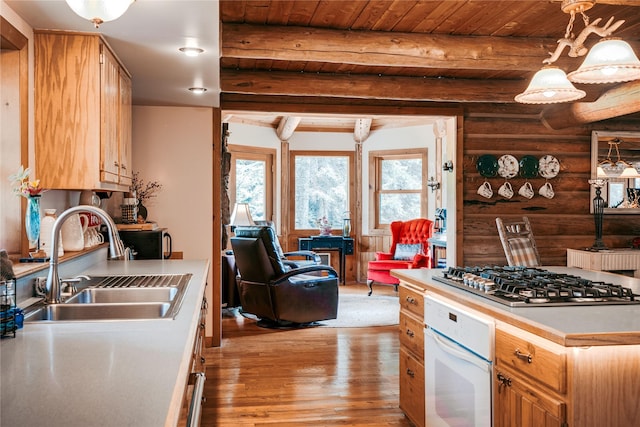 kitchen featuring a sink, log walls, white oven, light wood-style floors, and stainless steel gas cooktop