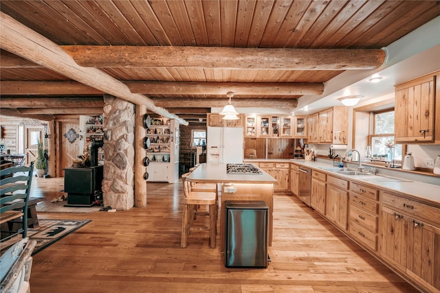 kitchen with a sink, stainless steel appliances, light brown cabinets, and a center island
