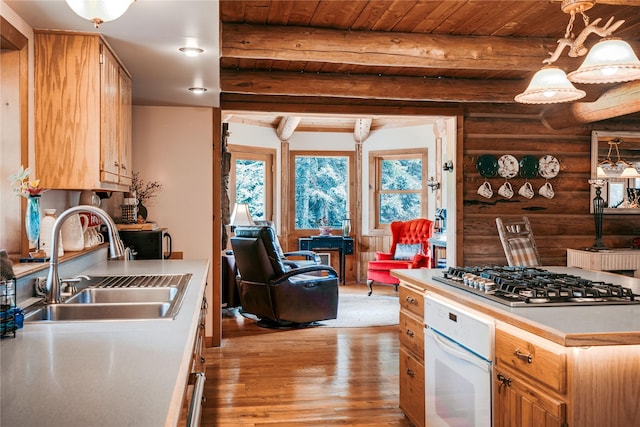 4212 Foothill Rd, Kalispell, MT 59901 - kitchen featuring stainless steel gas stovetop, white oven, rustic walls, healthy amount of natural light, and light wood-style flooring