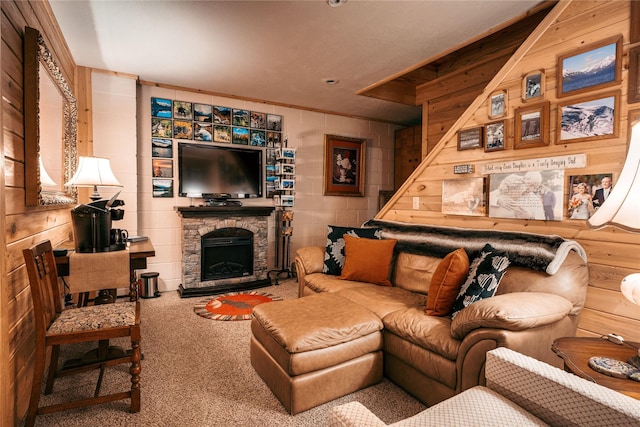 carpeted living room with wood walls, concrete block wall, and a stone fireplace