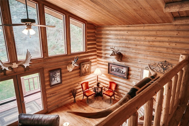 sitting room featuring wooden ceiling, rustic walls, wood finished floors, and ceiling fan