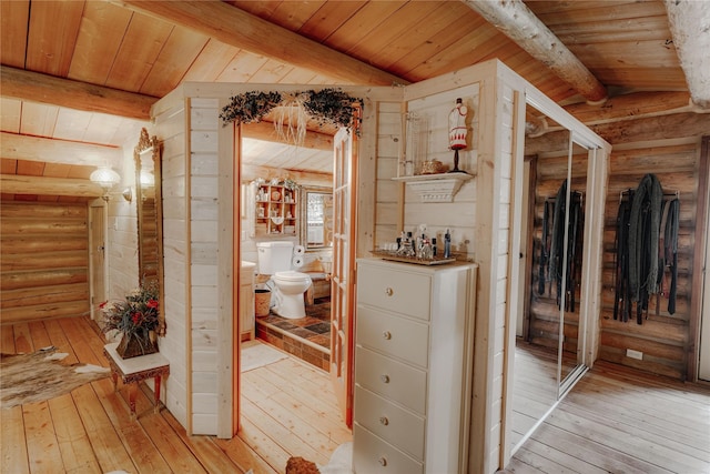corridor featuring lofted ceiling with beams, light wood finished floors, log walls, and wood ceiling