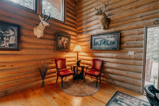 living area featuring a healthy amount of sunlight, log walls, and wood finished floors
