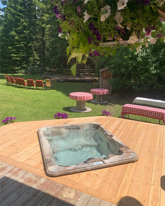 deck featuring hot tub deck surround and a lawn