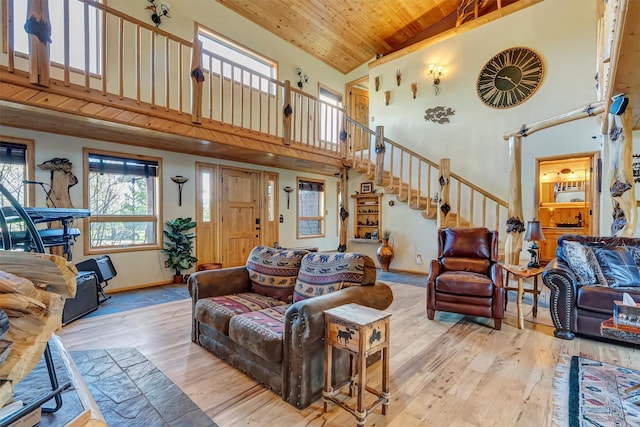 living area with high vaulted ceiling, hardwood / wood-style floors, stairs, wooden ceiling, and baseboards
