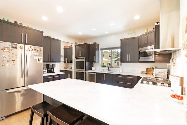 kitchen featuring a peninsula, dark brown cabinetry, stainless steel appliances, and a sink