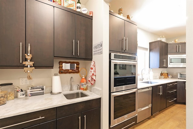 kitchen featuring a sink, dark brown cabinetry, light countertops, and appliances with stainless steel finishes