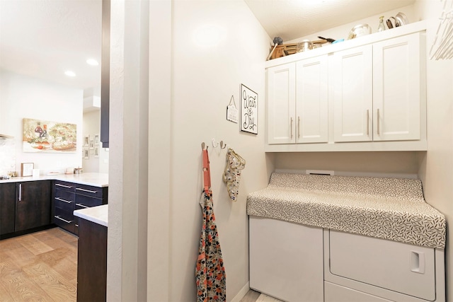clothes washing area featuring light wood finished floors and recessed lighting