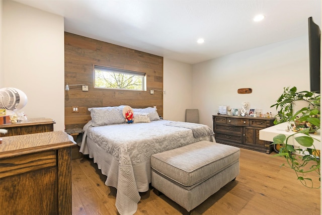 bedroom featuring wood walls, light wood-style flooring, recessed lighting, and an accent wall