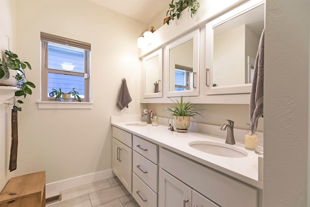 bathroom featuring double vanity, visible vents, baseboards, and a sink