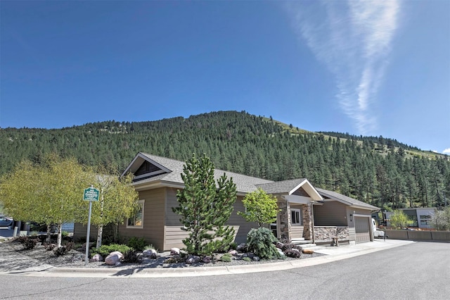 view of front facade featuring a forest view, a mountain view, and an attached garage