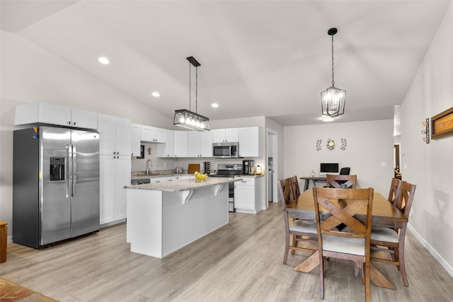 kitchen with lofted ceiling, stainless steel appliances, light wood finished floors, and white cabinets