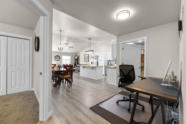 office area featuring vaulted ceiling, ceiling fan, light wood-style flooring, and baseboards