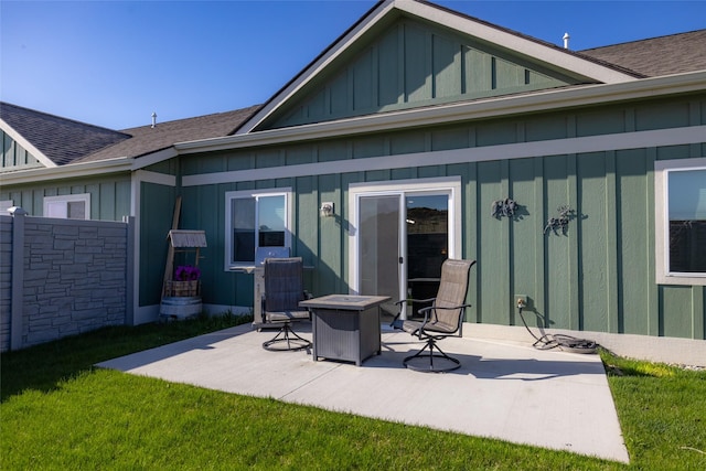 back of property with a yard, board and batten siding, a patio, and roof with shingles