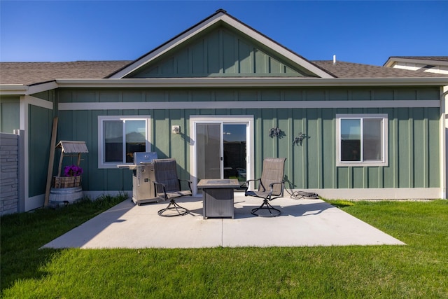 back of house featuring board and batten siding, a patio, roof with shingles, and a lawn