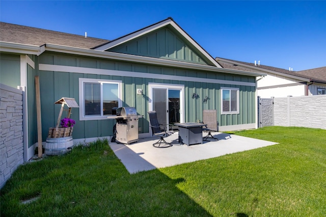 back of property featuring fence, a fire pit, a yard, a patio, and board and batten siding