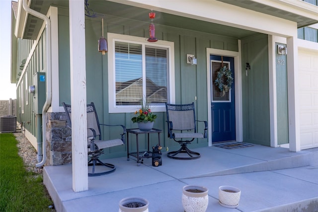 entrance to property with a porch, an attached garage, cooling unit, and board and batten siding