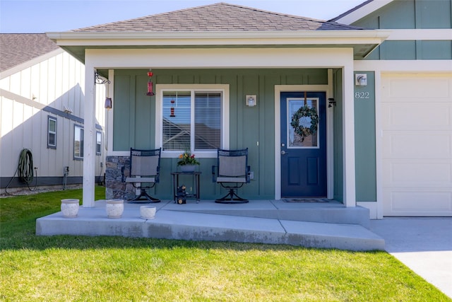 view of exterior entry with a yard, board and batten siding, a shingled roof, and covered porch