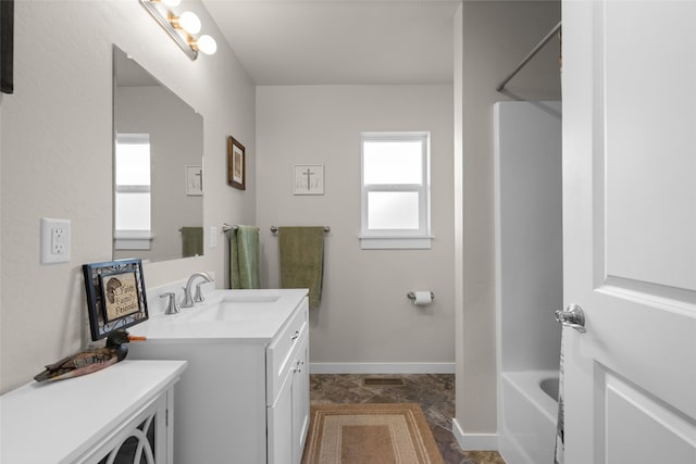 bathroom featuring bathing tub / shower combination, baseboards, and vanity