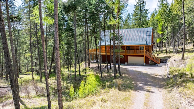 148 Muley Rd, Lakeside, MT 59922 - view of front facade featuring stairs, a garage, metal roof, dirt driveway, and a forest view