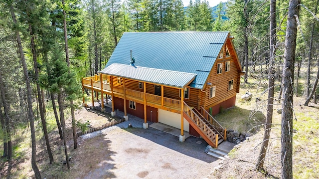 148 Muley Rd, Lakeside, MT 59922 - rear view of house with log siding, an attached garage, a wooden deck, dirt driveway, and a standing seam roof