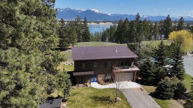 exterior space with a garage, a water and mountain view, a front yard, a balcony, and driveway