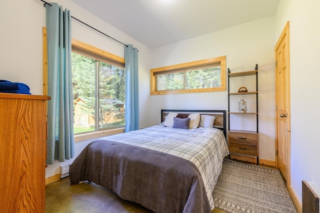 bedroom featuring a baseboard heating unit, baseboards, and multiple windows