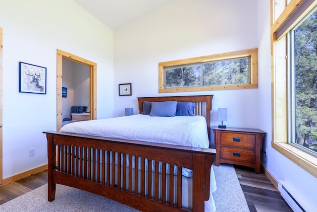 bedroom featuring baseboards, wood finished floors, baseboard heating, and a high ceiling