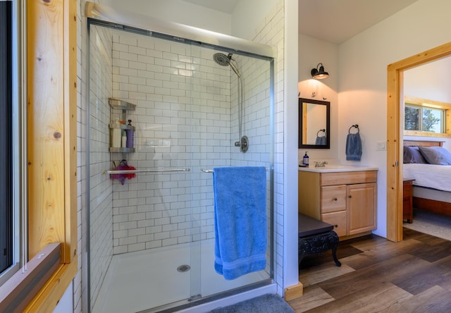 ensuite bathroom with a stall shower, vanity, connected bathroom, and wood finished floors