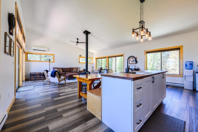 kitchen with a sink, white cabinetry, butcher block counters, vaulted ceiling, and a baseboard radiator